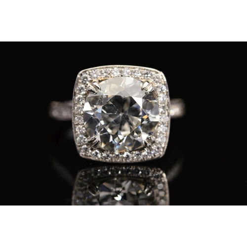 50 - A STUNNING MODERN LARGE DIAMOND RING, centring on a transitional round brilliant cut diamond, enclos... 