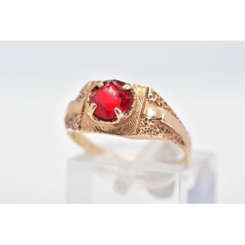 144 - A RING, set with a circular cut red paste within a four claw setting to the textured surround and sh... 