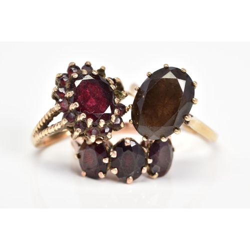 43 - THREE GEM SET RINGS, the first set with an oval smoky quartz, the second an oval garnet within a cir... 