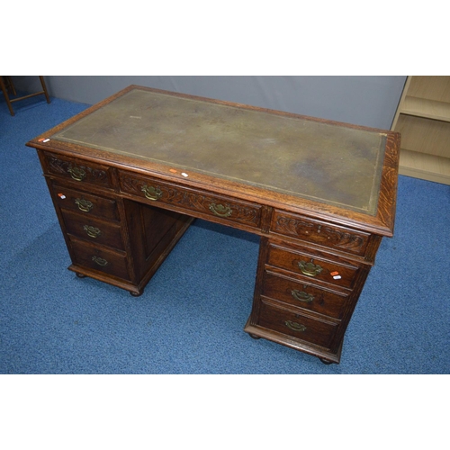 1685 - AN EARLY 20TH CENTURY CARVED OAK PEDESTAL DESK, dark green gilt tooled leather inlay top and nine as... 