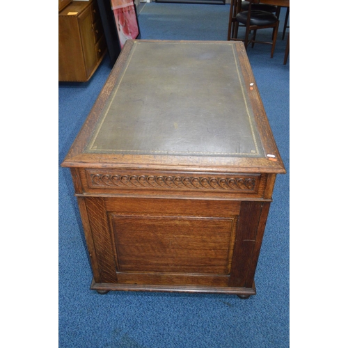 1685 - AN EARLY 20TH CENTURY CARVED OAK PEDESTAL DESK, dark green gilt tooled leather inlay top and nine as... 