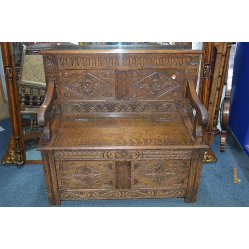 1695 - A REPRODUCTION OAK HALL SETTLE, with four carved panels, hinged storage compartment flanked by open ... 