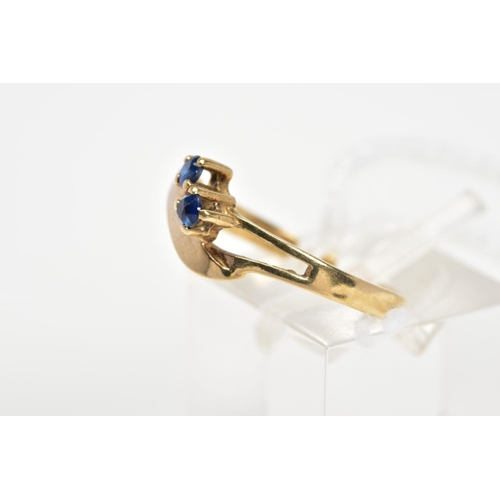 25 - A 9CT GOLD SAPPHIRE DRESS RING, of asymmetric design and split front band, diagonally set with two c... 