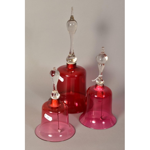 349 - THREE VICTORIAN GLASS BELLS, with cranberry tinted bowls and turned handles, of various heights, tal... 