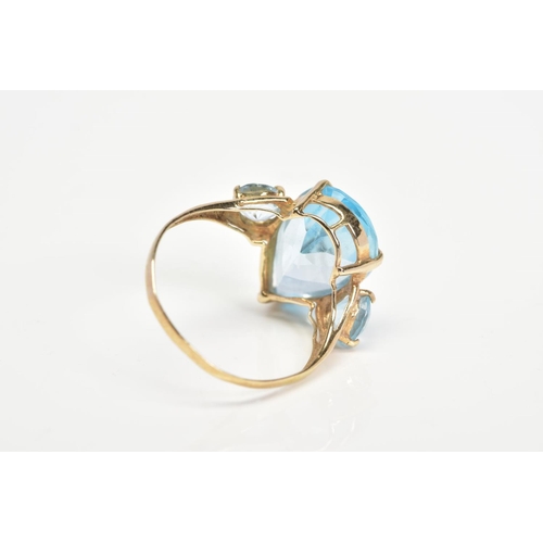 4 - A THREE STONE TOPAZ DRESS RING, designed as a central pear shape topaz within a three claw setting f... 