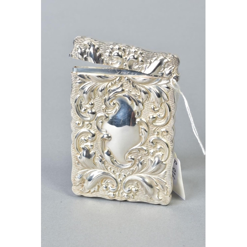 95 - AN EDWARDIAN SILVER CARD CASE OF WAVY RECTANGULAR OUTLINE, repousse decorated with foliate scrolls, ... 