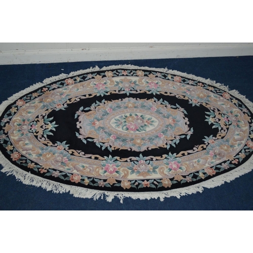 1291 - A LARGE G H FIRTH OVAL WOOLLEN CHINESE BLACK GROUND RUG, 250cm x 160cm and a similar smaller rug (2)