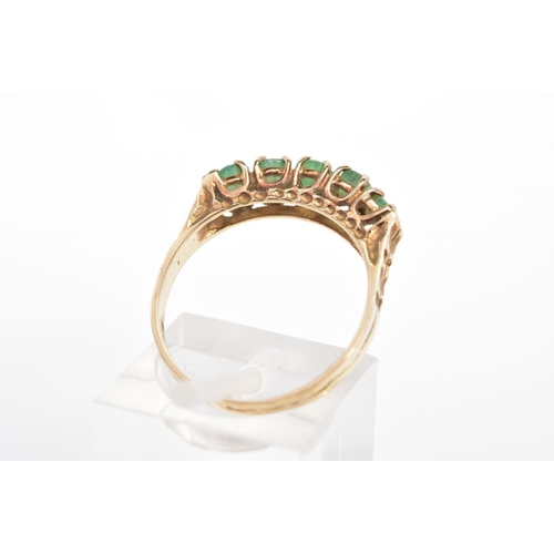 52 - A 9CT GOLD EMERALD RING, set with a row of five circular cut emeralds to the engraved shoulders, wit... 