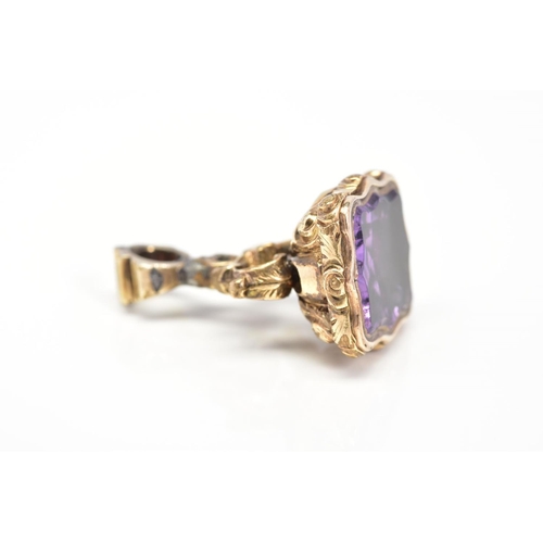 69 - A FOB, set with a shaped amethyst panel, with scroll design grip, length 25mm