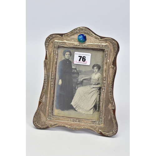 76 - AN EARLY 20TH CENTURY SILVER FRONTED PHOTO FRAME, with embossed floral and foliate detail and a circ... 