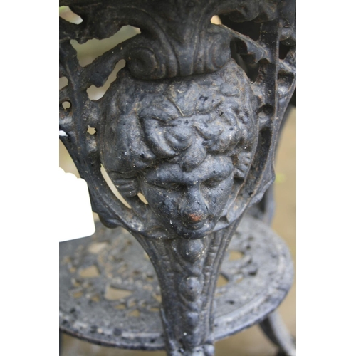 1016 - A CAST IRON PUB TABLE with a black painted base, female face mask detail to the tops of all three le... 