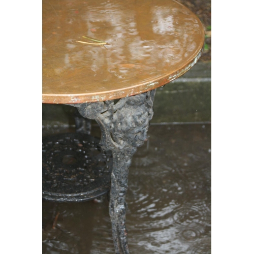 1019 - A CAST IRON PUB TABLE with a black painted base, female face mask detail to the tops of all three le... 