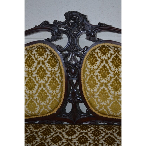 1202 - A VICTORIAN MAHOGANY FOLIATE UPHOLSTERED TWO SEATER SERPENTINE FRONTED SETTEE, flanked with two back... 