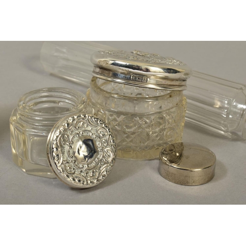 123 - FOUR EARLY 20TH CENTURY SILVER TOPPED GLASS TOILET JARS, two cylindrical and two circular, including... 