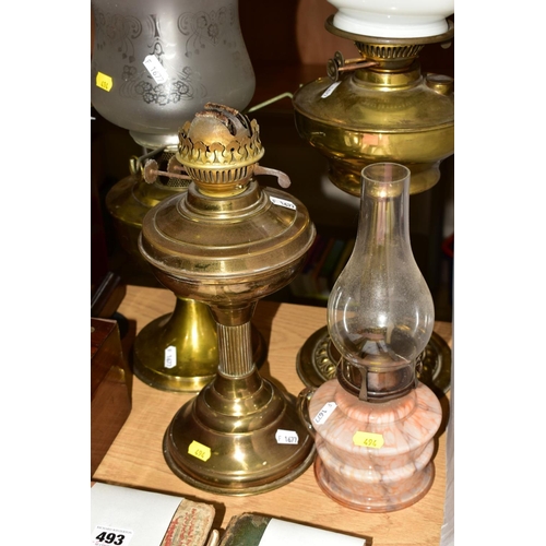 494 - FOUR OIL LAMPS, comprising three brass based oil lamps, two with chimneys and shades and a small gla... 