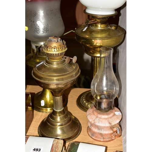 494 - FOUR OIL LAMPS, comprising three brass based oil lamps, two with chimneys and shades and a small gla... 