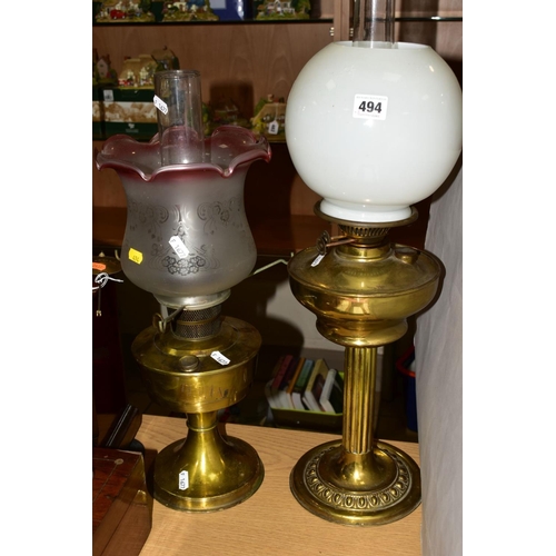 494 - FOUR OIL LAMPS, comprising three brass based oil lamps, two with chimneys and shades and a small gla... 