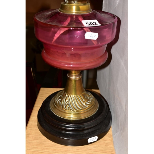 502 - A LATE VICTORIAN CRANBERRY GLASS AND BRASS OIL LAMP, the wavy rimmed shade acid etched with floral d... 