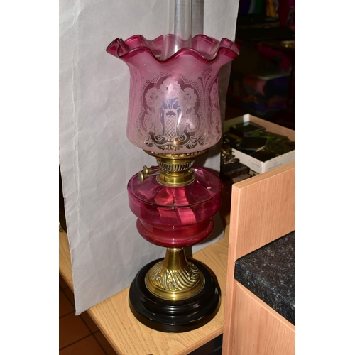 502 - A LATE VICTORIAN CRANBERRY GLASS AND BRASS OIL LAMP, the wavy rimmed shade acid etched with floral d... 