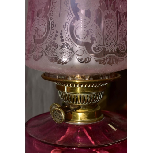 502 - A LATE VICTORIAN CRANBERRY GLASS AND BRASS OIL LAMP, the wavy rimmed shade acid etched with floral d... 