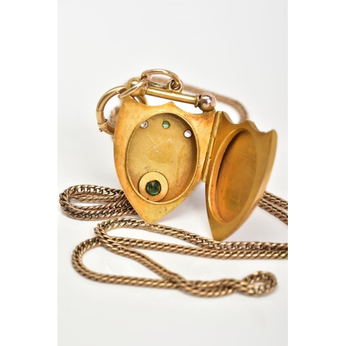 14 - AN EARLY 20TH CENTURY GOLD SHIELD SHAPED LOCKET, set with green and white paste stone, together with... 