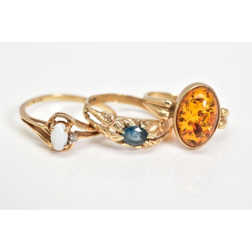 143 - THREE GEM SET RINGS, the first ring designed with an oval cabochon amber, with detailed shoulders, w... 