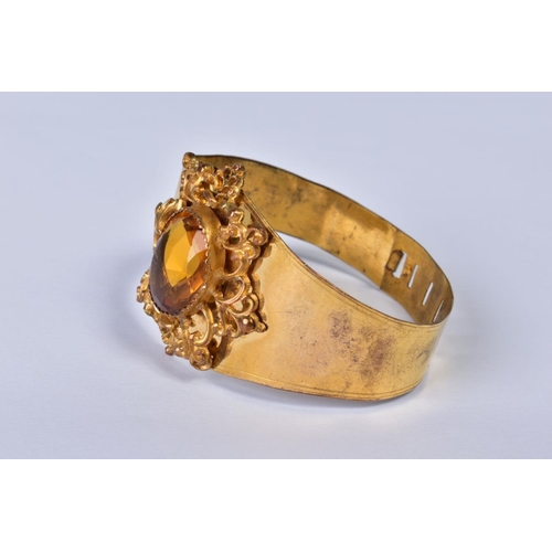 151 - A VICTORIAN GILT METAL BANGLE, the foliate scroll mount set with a central facet cut citrine, taperi... 