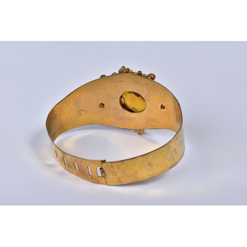 151 - A VICTORIAN GILT METAL BANGLE, the foliate scroll mount set with a central facet cut citrine, taperi... 