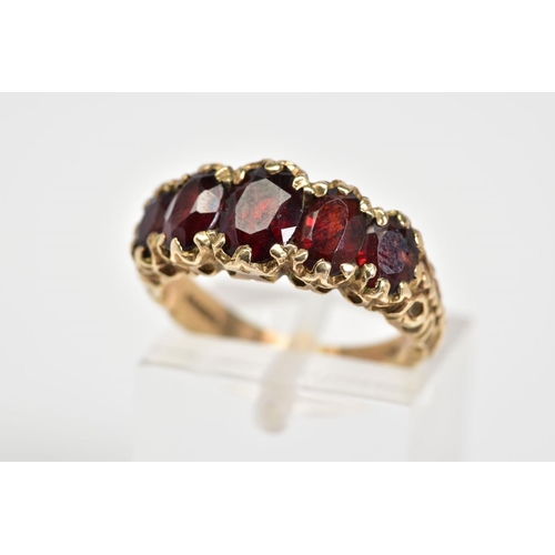 46 - A 9CT GOLD FIVE STONE RING, set with five oval cut garnets, scrolling detail to gallery and shoulder... 