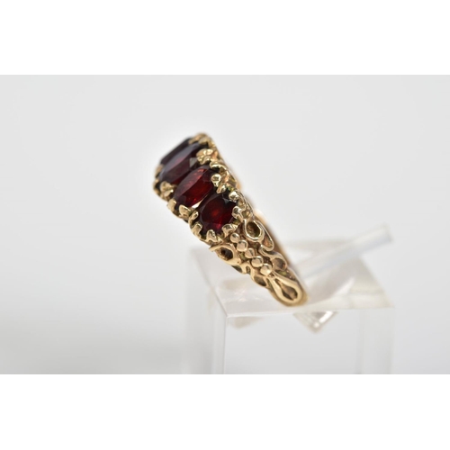 46 - A 9CT GOLD FIVE STONE RING, set with five oval cut garnets, scrolling detail to gallery and shoulder... 