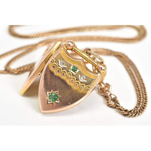 14 - AN EARLY 20TH CENTURY GOLD SHIELD SHAPED LOCKET, set with green and white paste stone, together with... 