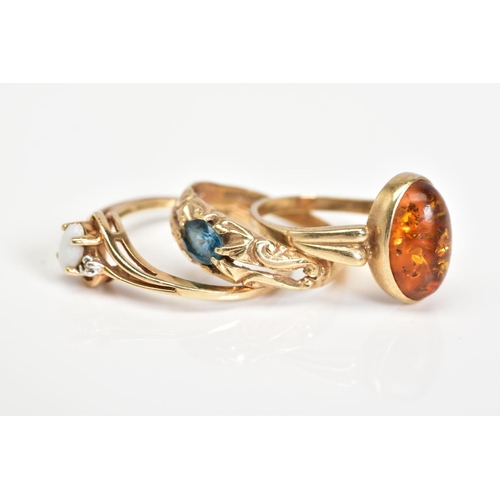 143 - THREE GEM SET RINGS, the first ring designed with an oval cabochon amber, with detailed shoulders, w... 