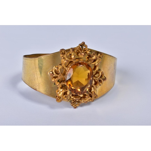 151 - A VICTORIAN GILT METAL BANGLE, the foliate scroll mount set with a central facet cut citrine, taperi... 