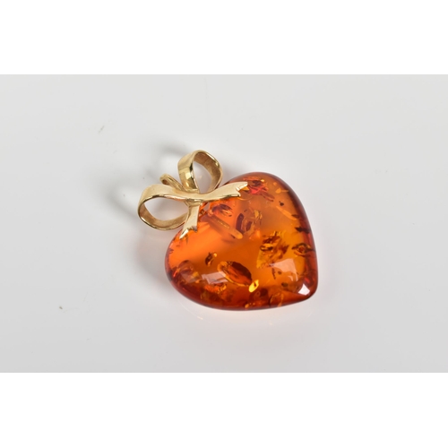 3 - A MODERN 14CT GOLD AMBER HEART PENDANT, measuring approximately 23mm in diameter, fancy bow pendant ... 