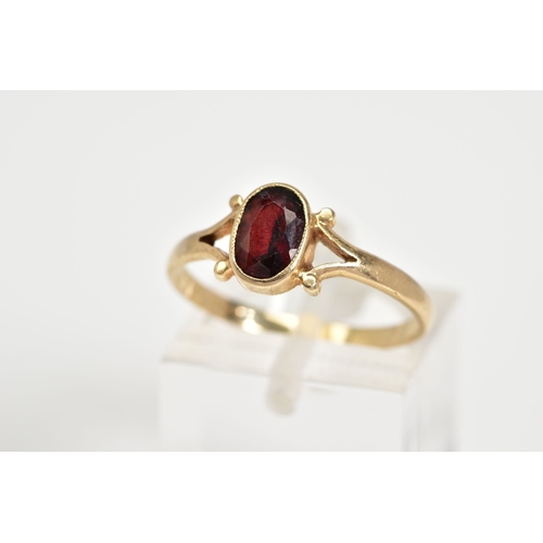 50 - A 9CT GOLD GARNET RING, set with a central oval cut garnet to the bifurcated shoulders and plain pol... 