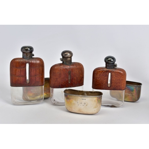 181 - A SET OF THREE GRADUATED SILVER AND CROCODILE SKIN GLASS HIP FLASKS with quarter turn caps