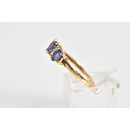 10 - AN 18CT GOLD TANZANITE AND DIAMOND RING, designed with three oval cut tanzanite's interspaced with r... 