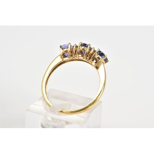 10 - AN 18CT GOLD TANZANITE AND DIAMOND RING, designed with three oval cut tanzanite's interspaced with r... 