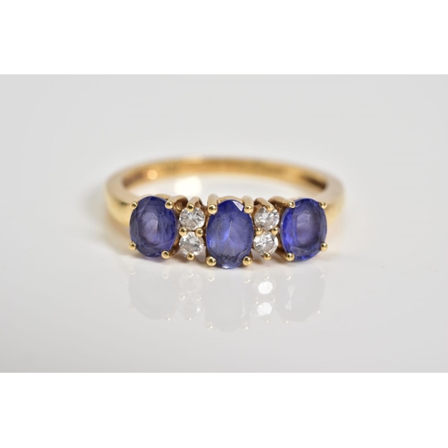 10 - AN 18CT GOLD TANZANITE AND DIAMOND RING, designed with three oval cut tanzanite's interspaced with r... 