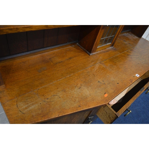 1251 - AN EARLY 20TH CENTURY OAK ARTS & CRAFTS SIDEBOARD, the top with shelves flanking a single lead glaze... 