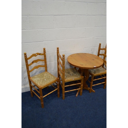 1279 - A MODERN PINE CIRCULAR KITCHEN TABLE, and four rush seated ladder back chairs (one chair with s.d.),... 