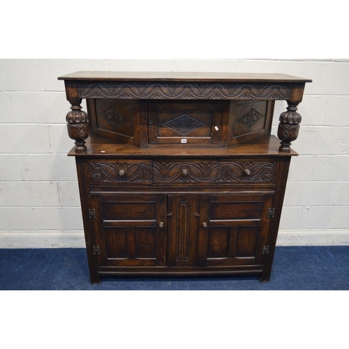 1304 - AN EARLY TO MID 20TH CENTURY CARVED OAK COURT CUPBOARD, the overhanging top flanking with acorn supp... 