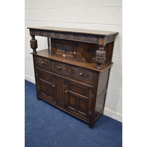 1304 - AN EARLY TO MID 20TH CENTURY CARVED OAK COURT CUPBOARD, the overhanging top flanking with acorn supp... 