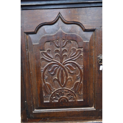 1310 - AN 18TH CENTURY AND LATER CARVED OAK TWO DOOR DEUDDARN, carved triple panel front, above two drawers... 