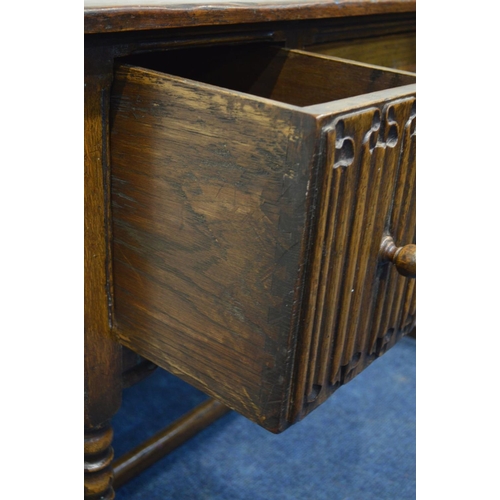 1311 - A REPRODUCTION OAK DESK, with two deep linenfold front drawers flanking a single drawer, on turned f... 