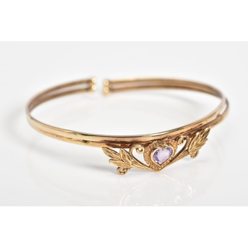 19 - AN AMETHYST SET BANGLE, set with a central heart shaped amethyst within a floral detail panel, to th... 