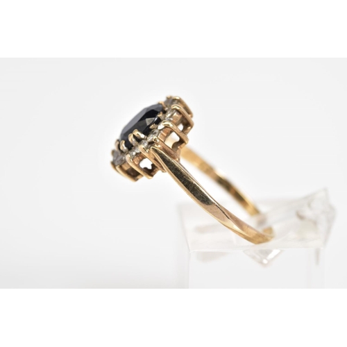 28 - A 9CT GOLD CLUSTER RING, set with a central oval cut sapphire with a cut cubic zirconia surround, to... 