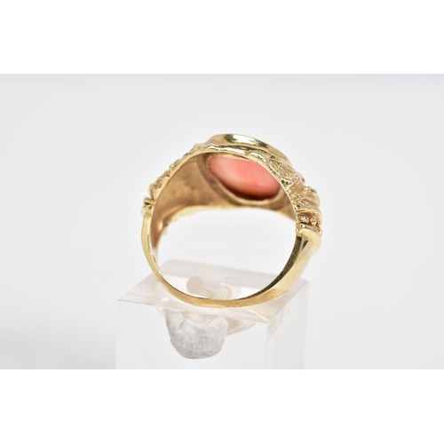 4 - A CORAL SET RING, the yellow metal ring designed with a central oval coral panel within a collet mou... 