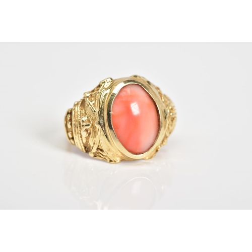 4 - A CORAL SET RING, the yellow metal ring designed with a central oval coral panel within a collet mou... 