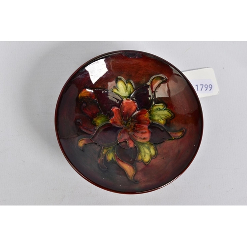 562 - A MOORCROFT POTTERY FLAMBE PIN DISH, Columbine design to centre, on a circular foot, restoration to ... 